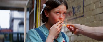 Movie still from “Pearl” (2022), directed by Ti West – A young girl is eating something with her hands; Close Up shot, High angle