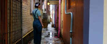 Movie still from “Pearl” (2022), directed by Ti West – A woman standing in an alleyway looking at a fire hydrant; Wide shot, High angle
