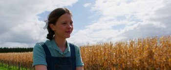 Movie still from “Pearl” (2022), directed by Ti West – A young girl standing in front of a corn field; Close Up shot, Low angle