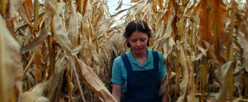 Movie still from “Pearl” (2022), directed by Ti West – A woman standing in a corn field looking down; Medium shot, Low angle