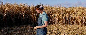 Movie still from “Pearl” (2022), directed by Ti West – A woman standing in front of a corn field; Medium shot, Low angle