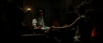 Movie still from “Pearl” (2022), directed by Ti West – A man sitting at a table in a dark room; Medium shot, Low angle
