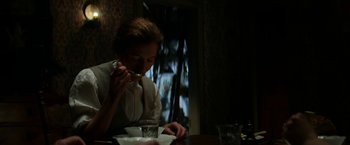 Movie still from “Pearl” (2022), directed by Ti West – A woman sitting at a table eating a meal; Medium shot, Low angle