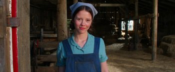 Movie still from “Pearl” (2022), directed by Ti West – A young girl wearing a blue apron and a blue hat; Close Up shot, Low angle