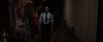 Movie still from “Pearl” (2022), directed by Ti West – A man wearing a tie and suspenders walking down stairs; Medium shot, Low angle