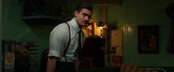 Movie still from “Pearl” (2022), directed by Ti West – A man wearing a tie and suspenders standing in a room; Medium shot, Over the shoulder angle