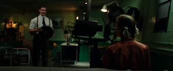 Movie still from “Pearl” (2022), directed by Ti West – A man sitting in front of a projector in a room; Wide shot, High angle