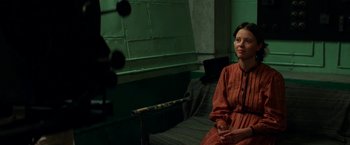 Movie still from “Pearl” (2022), directed by Ti West – A woman sitting on a couch in front of a microphone; Medium shot, Over the shoulder angle