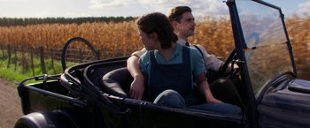 Movie still from “Pearl” (2022), directed by Ti West – A man and a woman riding in the back of a carriage; Medium shot, Over the shoulder angle