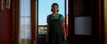 Movie still from “Pearl” (2022), directed by Ti West – A woman standing in front of an open door; Medium shot, Low angle