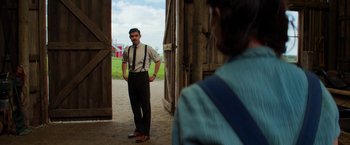 Movie still from “Pearl” (2022), directed by Ti West – A man standing in front of another man in front of a barn; Medium shot, Over the shoulder angle