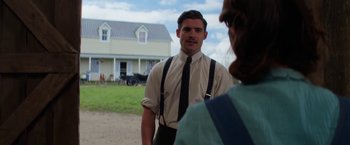 Movie still from “Pearl” (2022), directed by Ti West – A man in a suit and tie standing next to a woman in front of a house; Medium shot, Over the shoulder angle