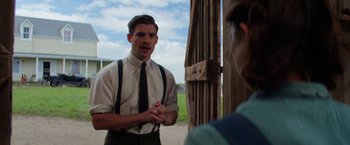 Movie still from “Pearl” (2022), directed by Ti West – A young man wearing a tie and suspenders talking to another man; Medium shot, Over the shoulder angle