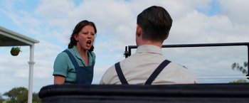 Movie still from “Pearl” (2022), directed by Ti West – A woman standing in front of a man in front of a sky background; Medium shot, Low angle