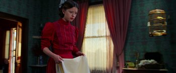 Movie still from “Pearl” (2022), directed by Ti West – A young girl in a red dress holding a sheet of paper; Medium shot, Low angle