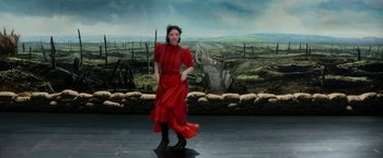 Movie still from “Pearl” (2022), directed by Ti West – A woman in a red dress standing in front of a painting; Wide shot, High angle