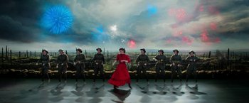 Movie still from “Pearl” (2022), directed by Ti West – A woman in a red dress standing in front of a group of soldiers; Wide shot, Overhead angle