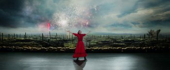 A woman in a red dress standing in front of fireworks