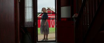 Movie still from “Pearl” (2022), directed by Ti West – A woman standing in front of an open door; Wide shot, Low angle