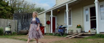Movie still from “Pearl” (2022), directed by Ti West – A woman walking in front of a house with a bike; Wide shot, Low angle