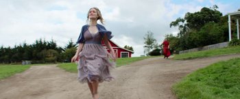 Movie still from “Pearl” (2022), directed by Ti West – A woman in a dress is walking down a dirt road; Wide shot, Low angle