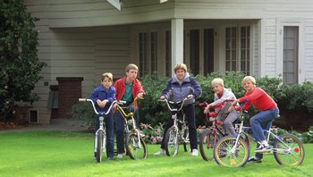 Movie still from “Pee-wee's Big Adventure” (1985), directed by Tim Burton – A group of people riding bikes in a yard; Wide shot, High angle
