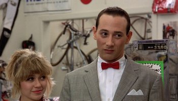Movie still from “Pee-wee's Big Adventure” (1985), directed by Tim Burton – A man wearing a suit and a red bow tie; Close Up shot, Over the shoulder angle