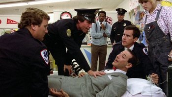 Movie still from “Pee-wee's Big Adventure” (1985), directed by Tim Burton – A group of men standing next to each other in a room; Medium shot, High angle