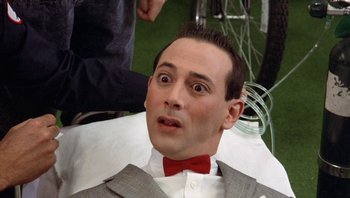 Movie still from “Pee-wee's Big Adventure” (1985), directed by Tim Burton – A person wearing a suit and a red bow tie; Close Up shot, High angle