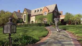 Movie still from “Pee-wee's Big Adventure” (1985), directed by Tim Burton – A person walking down a path in front of a house; Extreme Wide shot, Low angle