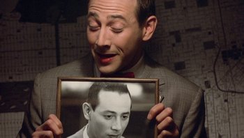 Movie still from “Pee-wee's Big Adventure” (1985), directed by Tim Burton – A man in a suit holding a picture of himself; Close Up shot, Over the shoulder angle