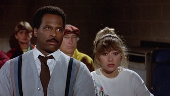 Movie still from “Pee-wee's Big Adventure” (1985), directed by Tim Burton – A man and a woman standing next to each other in front of another man; Close Up shot, Over the shoulder angle