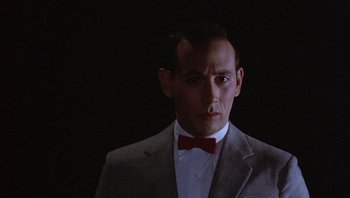 Movie still from “Pee-wee's Big Adventure” (1985), directed by Tim Burton – A man wearing a suit and a bow tie; Close Up shot, Low angle