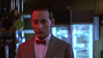 Movie still from “Pee-wee's Big Adventure” (1985), directed by Tim Burton – A man wearing a suit and a red bow tie; Close Up shot, Over the shoulder angle