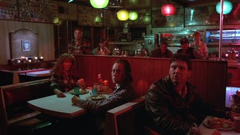 Movie still from “Pee-wee's Big Adventure” (1985), directed by Tim Burton – A group of people sitting at a table in a restaurant; Wide shot, High angle