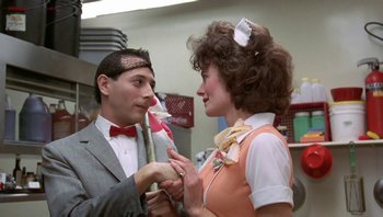 Movie still from “Pee-wee's Big Adventure” (1985), directed by Tim Burton – A man and a woman are dressed up for a party; Medium shot, Over the shoulder angle