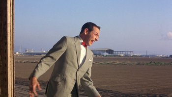 Movie still from “Pee-wee's Big Adventure” (1985), directed by Tim Burton – A man wearing a suit and a red bow tie; Medium shot, Low angle