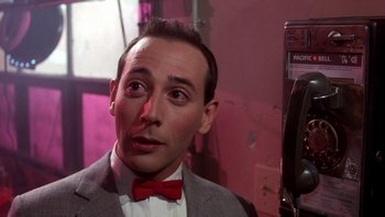 Movie still from “Pee-wee's Big Adventure” (1985), directed by Tim Burton – A person wearing a suit and a red bow tie; Close Up shot, Low angle
