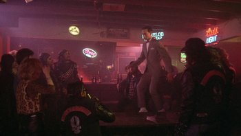 Movie still from “Pee-wee's Big Adventure” (1985), directed by Tim Burton – A man in a suit is dancing in a bar; Wide shot, Low angle
