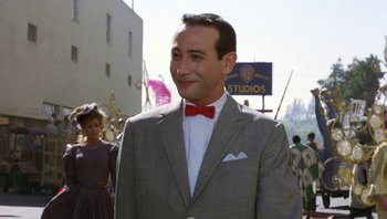 Movie still from “Pee-wee's Big Adventure” (1985), directed by Tim Burton – A man wearing a suit and a red bow tie; Medium shot, Over the shoulder angle