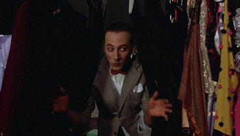 Movie still from “Pee-wee's Big Adventure” (1985), directed by Tim Burton – A man in a gray suit and a red bow tie; Medium shot, Low angle