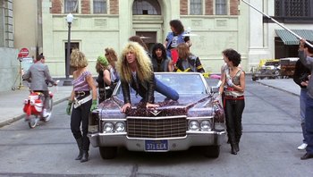 Movie still from “Pee-wee's Big Adventure” (1985), directed by Tim Burton – A group of people standing around a car; Wide shot, Low angle