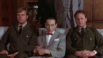 Movie still from “Pee-wee's Big Adventure” (1985), directed by Tim Burton – A group of men sitting in a room; Medium shot, Low angle