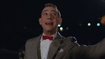 Movie still from “Pee-wee's Big Adventure” (1985), directed by Tim Burton – A person wearing a suit and a red bow tie; Close Up shot, Low angle