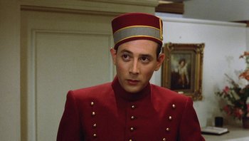 Movie still from “Pee-wee's Big Adventure” (1985), directed by Tim Burton – A man in a red suit and a hat; Close Up shot, Low angle
