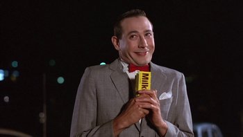 Movie still from “Pee-wee's Big Adventure” (1985), directed by Tim Burton – A man in a gray suit holding a box of milk chocolate; Close Up shot, Low angle
