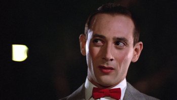 Movie still from “Pee-wee's Big Adventure” (1985), directed by Tim Burton – A person wearing a suit and a red bow tie; Close Up shot, Low angle