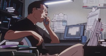 Movie still from “Perfect Blue” (1997), directed by Kô Matsuo – A man sitting in front of a computer talking on a phone; Medium shot, Low angle