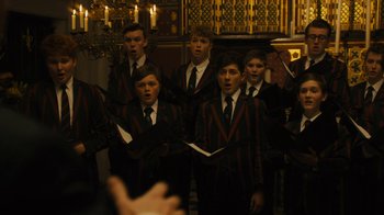 Movie still from “Philomena” (2013), directed by Stephen Frears – A group of young men standing next to each other in front of candles; Medium shot, Over the shoulder angle