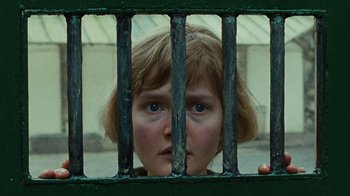 Movie still from “Philomena” (2013), directed by Stephen Frears – A woman looking through a metal fence; Close Up shot, Low angle